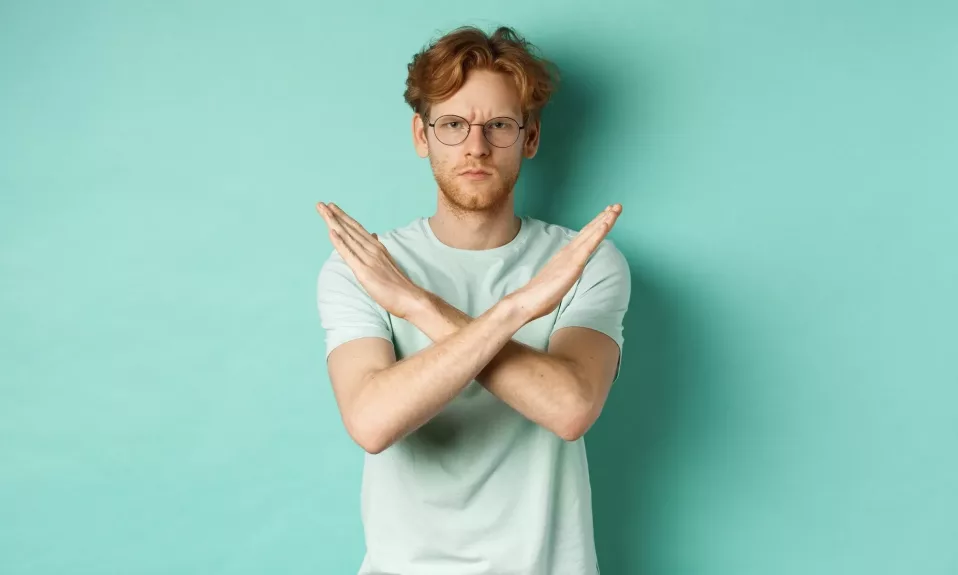 Man making "no" gesture with crossed arms.