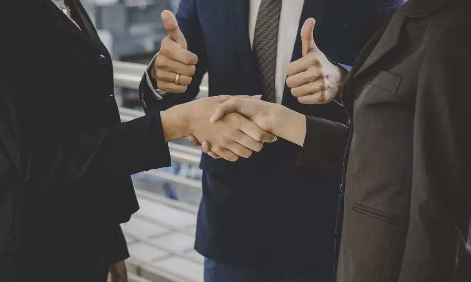 Business handshake and approval thumbs up gesture