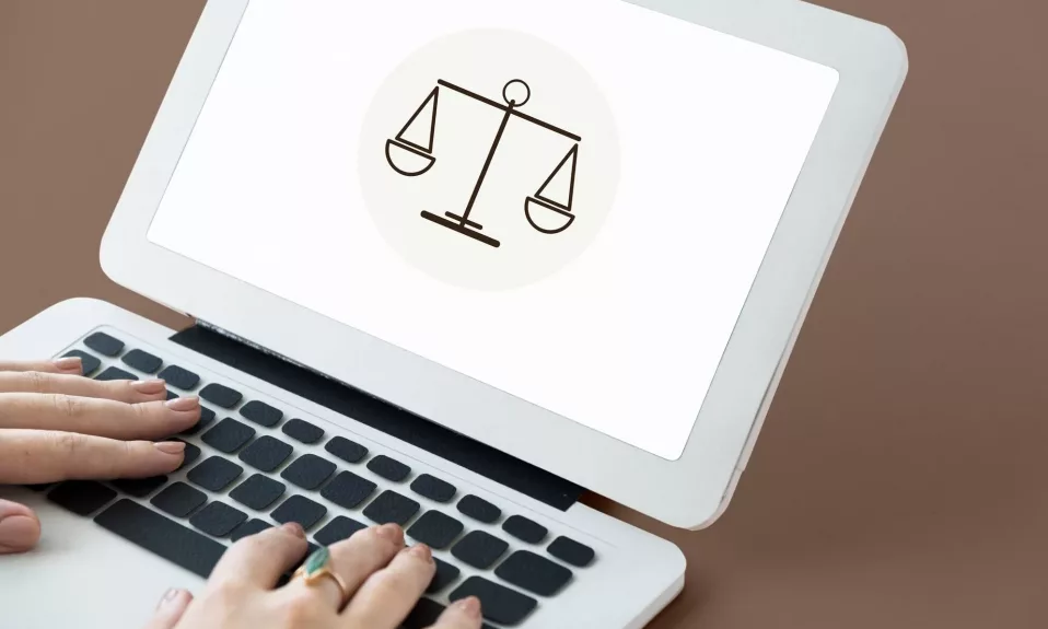 Person using laptop with scale of justice icon.