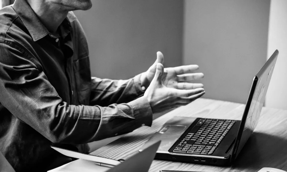 Man gesturing during a laptop meeting.