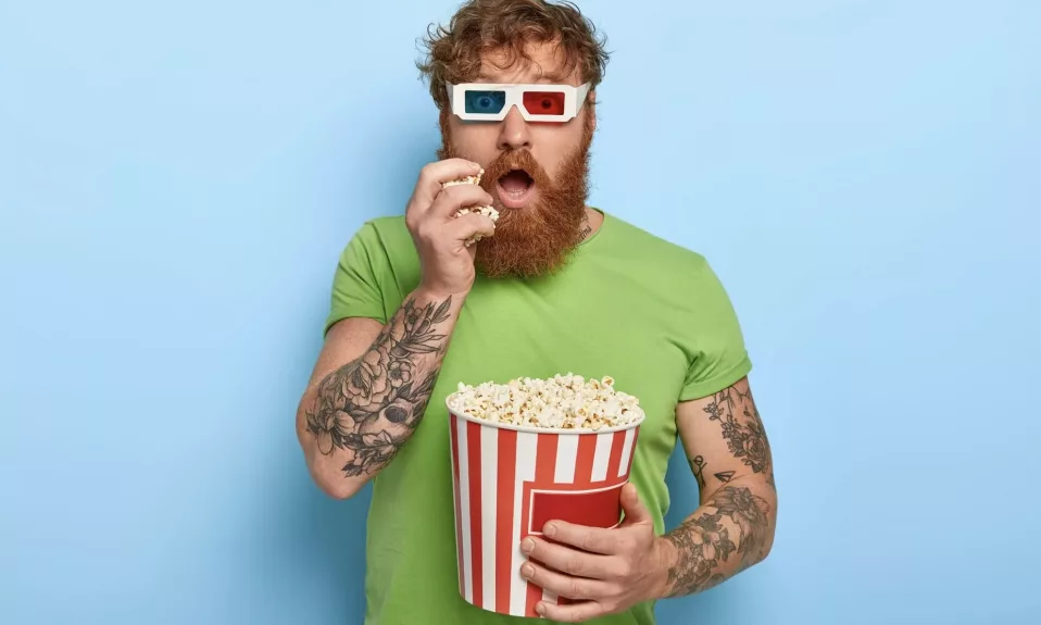 Man with 3D glasses eating popcorn.