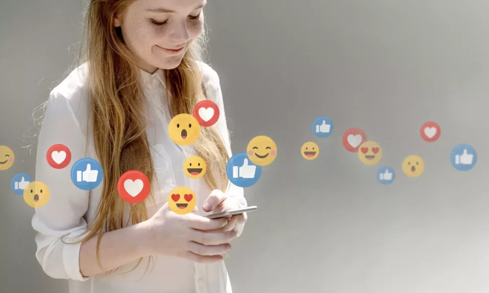 Woman using smartphone with floating social media emojis.