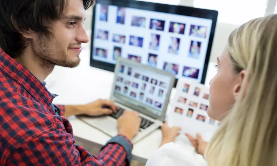 Two people browsing photos on computer screens.